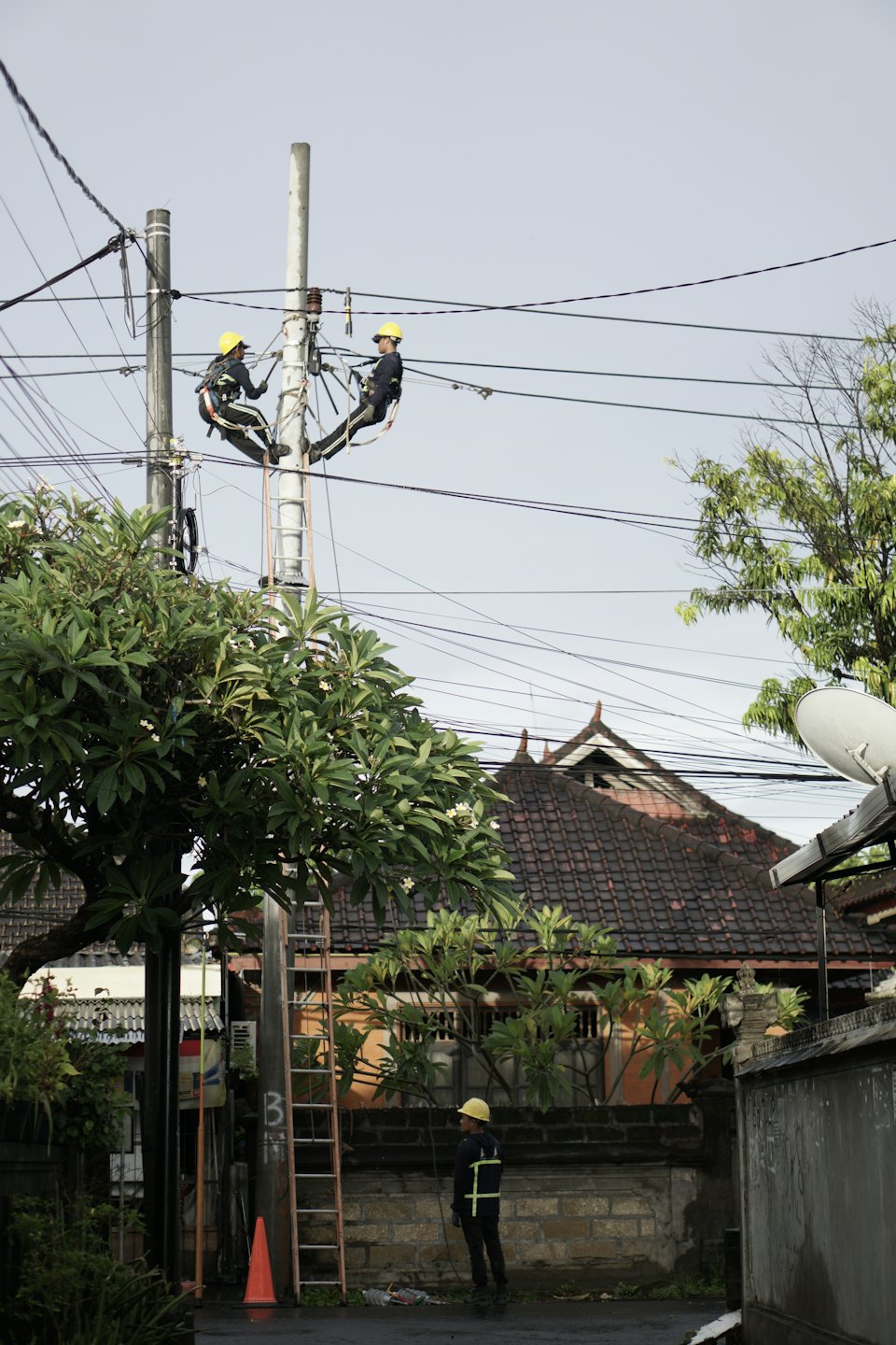 Utility technicians working on a utility pole with electrical wires.