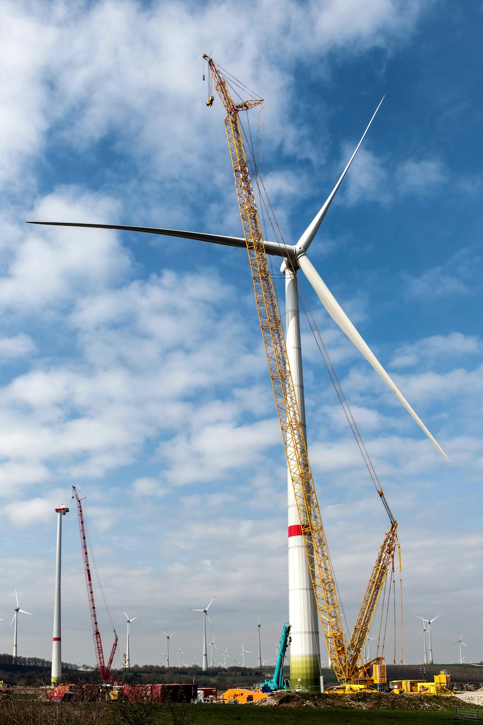 Yellow construction crane near a white wind turbine.