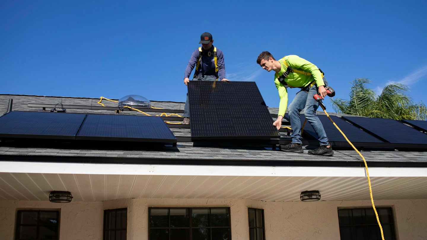 Workers installing solar panels on a residential roof.