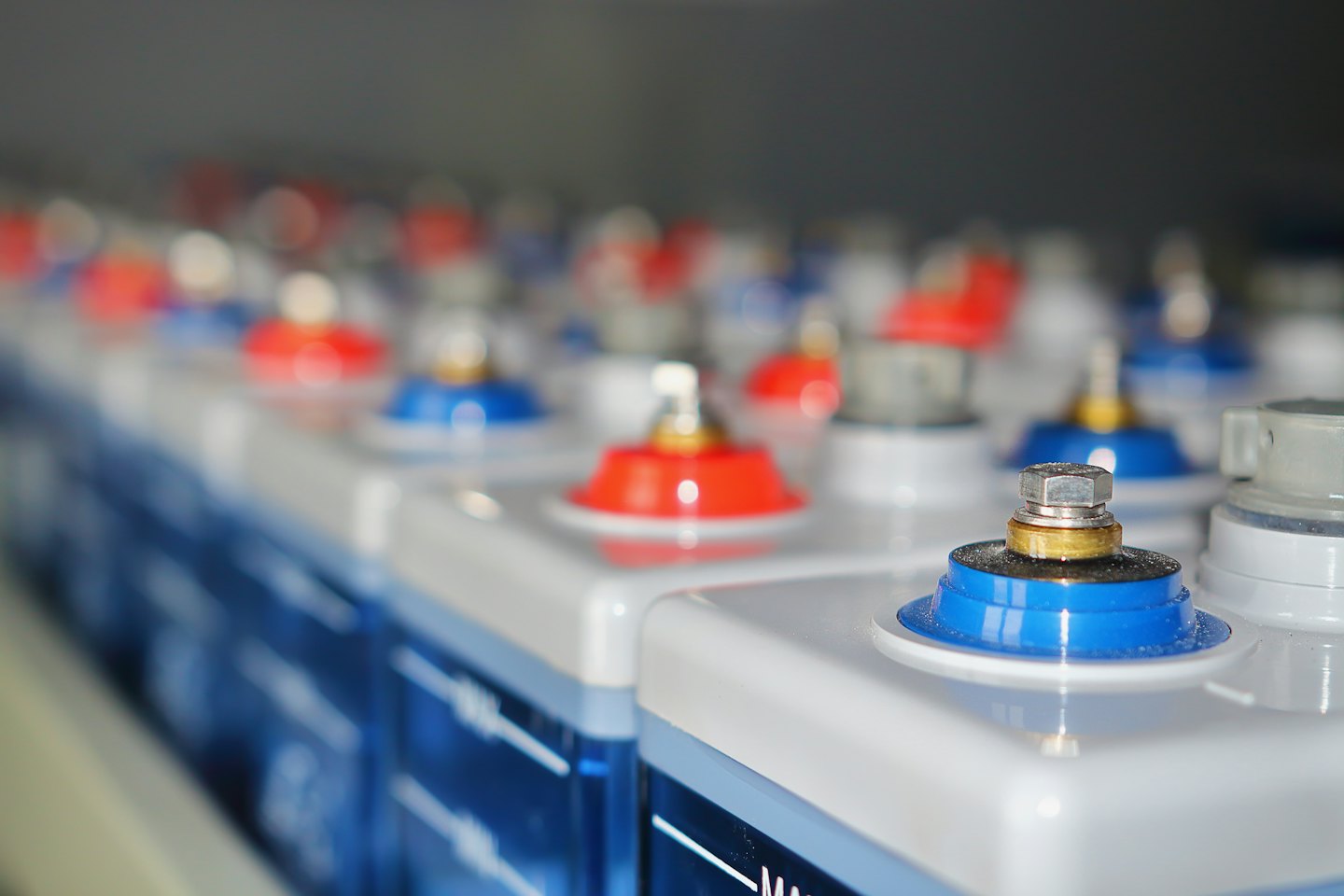 A row of industrial batteries with blue and red terminals.