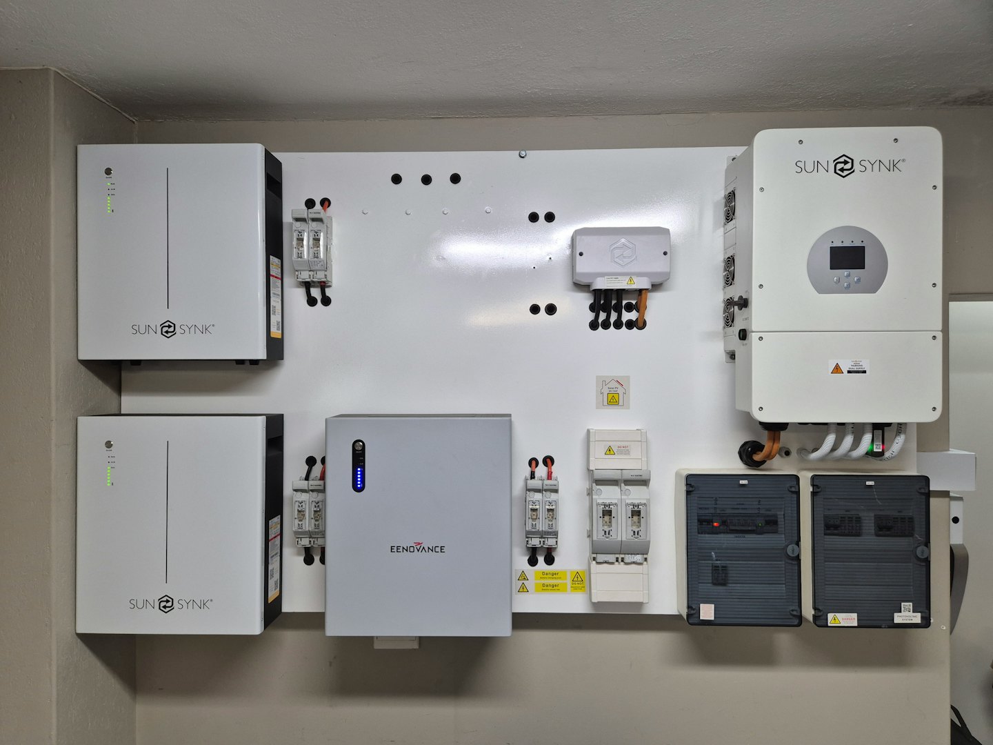 Home energy system with batteries and inverters on a white wall.