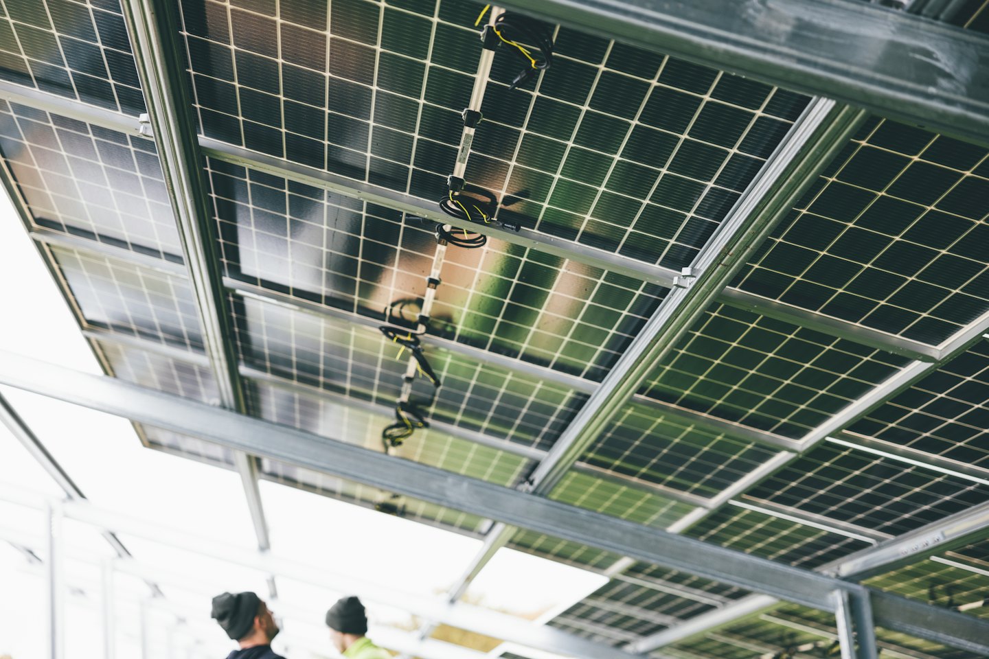 Inspectors examine a solar panel installation from below.